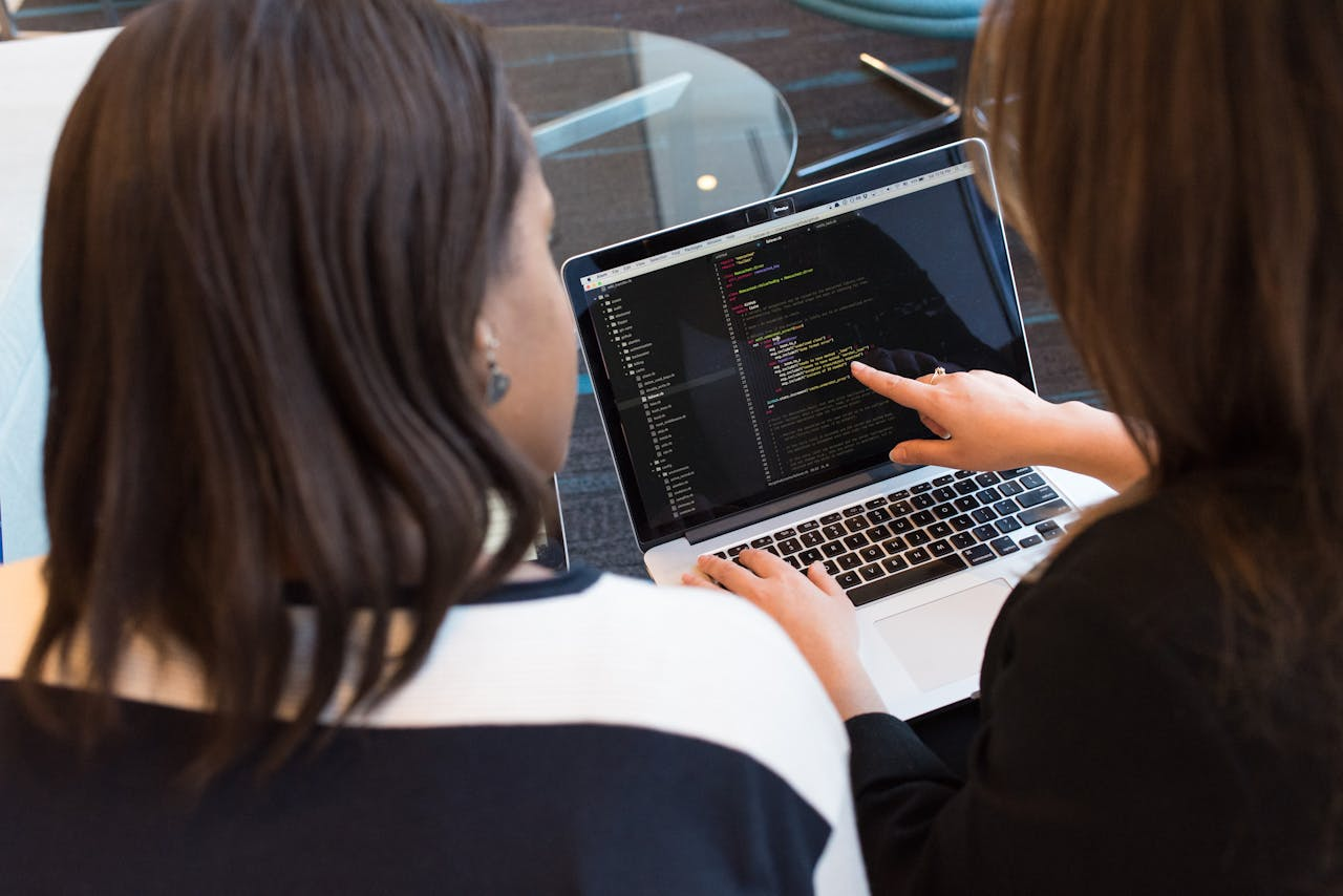 Home Two women working together on software programming indoors, focusing on code.