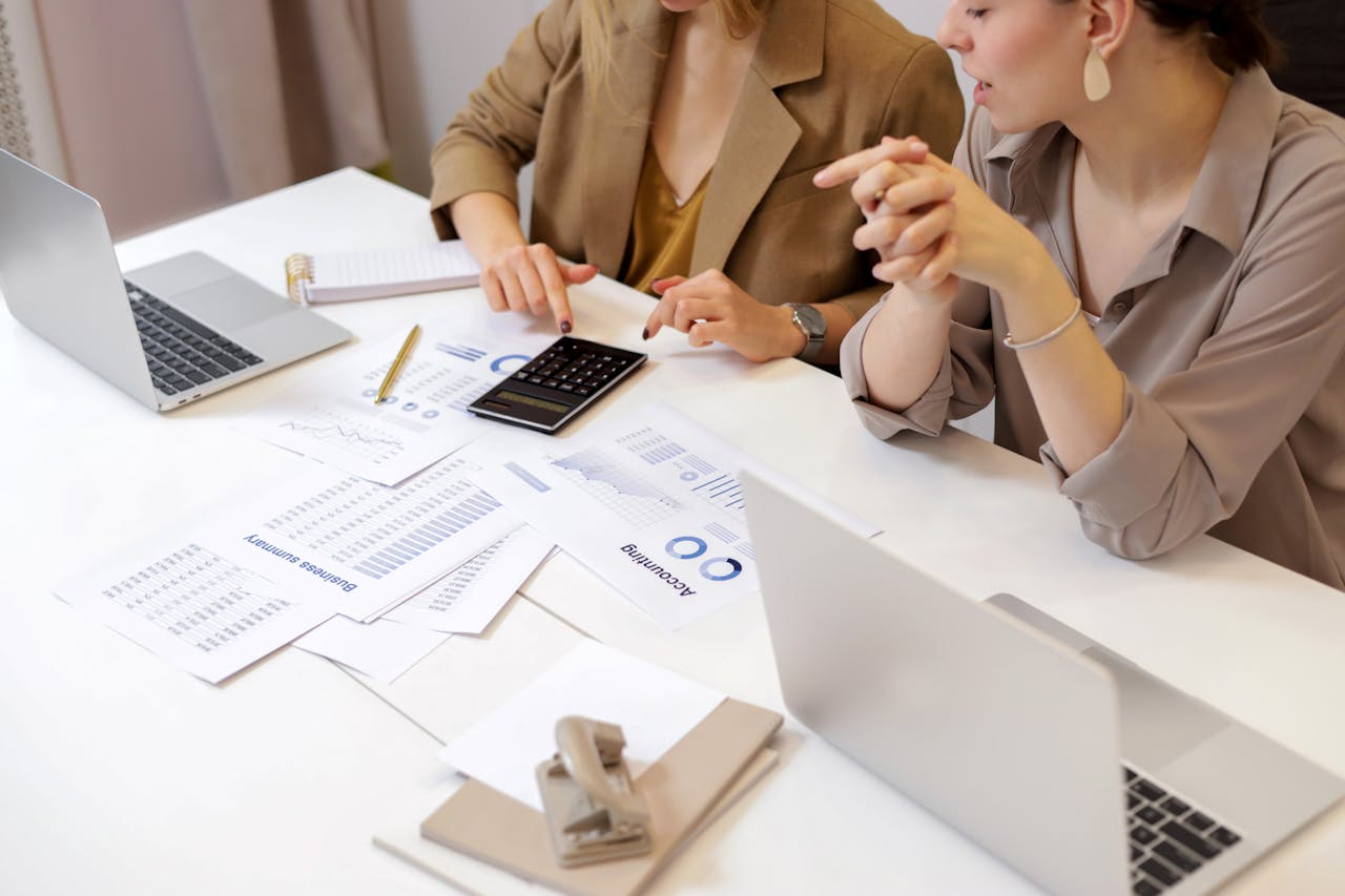 Services Two professionals collaborating on financial documents in a modern office setting.
